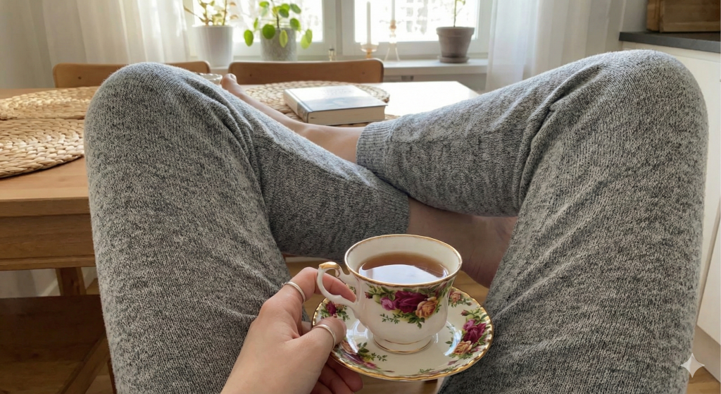 A glass of lemon water on a nightstand next to a face-down phone, prioritizing hydration over screen time.